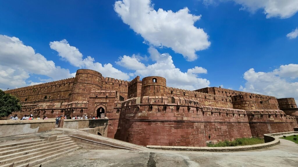Amazing architectural detail of Agra Fort with tourists enjoying a sunny day under a clear blue sky.